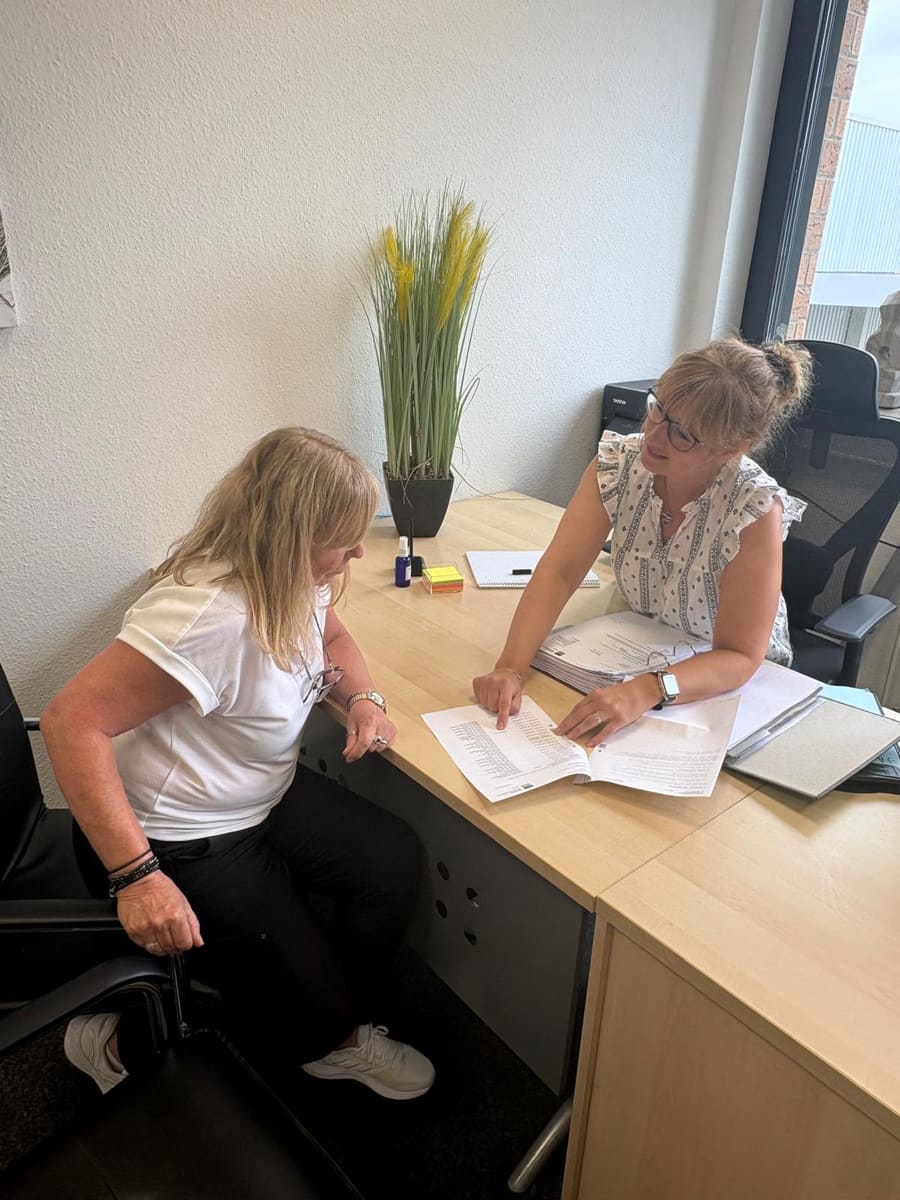 Zwei Mitarbeiterinnen im Gespräch am Schreibtisch im Büro